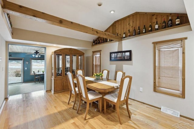 dining space with light wood-style floors, visible vents, vaulted ceiling, and a ceiling fan