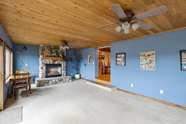 unfurnished living room featuring wooden ceiling, a fireplace, a ceiling fan, baseboards, and carpet