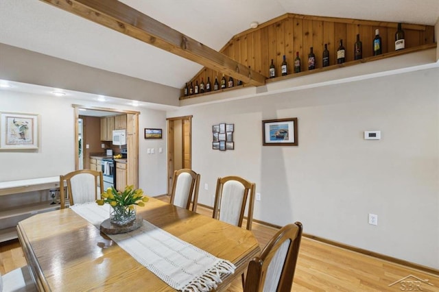 dining space with vaulted ceiling with beams, light wood-type flooring, and baseboards