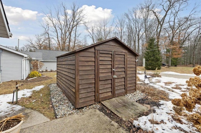 snow covered structure featuring a storage unit and an outbuilding