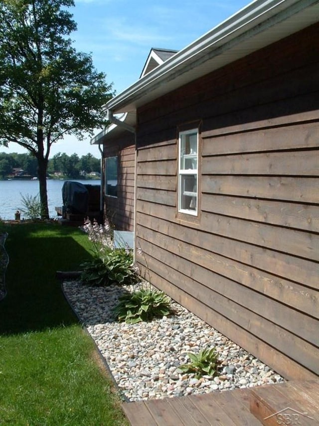 view of side of home with a water view and a lawn