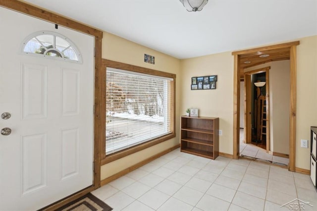 entryway with light tile patterned floors, a wealth of natural light, and baseboards