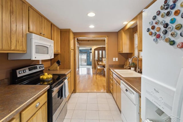 kitchen with white appliances, brown cabinetry, light tile patterned flooring, a sink, and recessed lighting