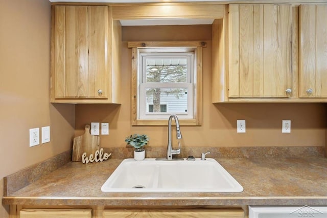 kitchen featuring dishwashing machine, a sink, and light brown cabinetry