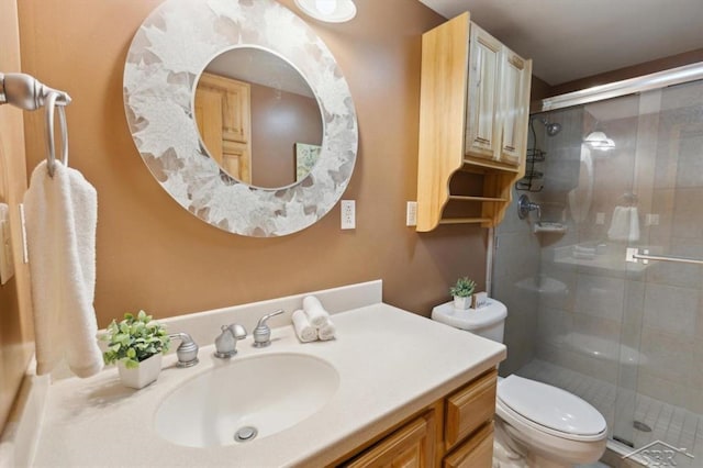 bathroom with a shower stall, toilet, and vanity