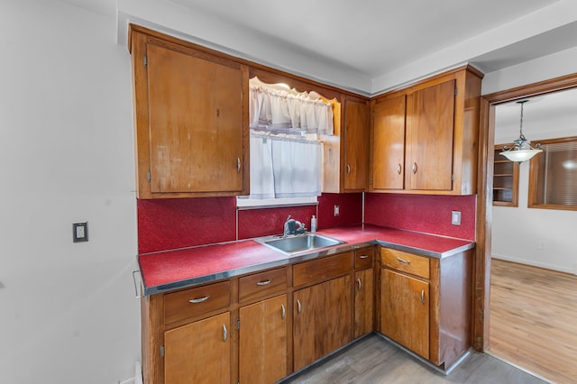 kitchen with brown cabinetry, light wood-type flooring, a sink, and decorative backsplash