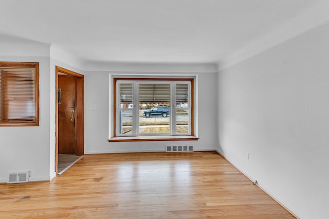 unfurnished room with light wood-style floors, visible vents, and baseboards