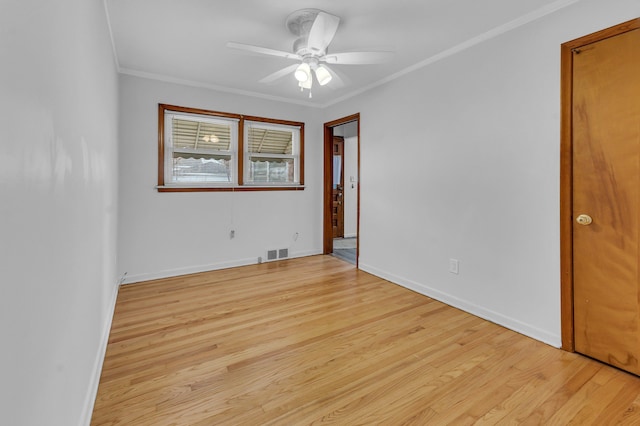 spare room with ceiling fan, visible vents, baseboards, light wood-type flooring, and crown molding