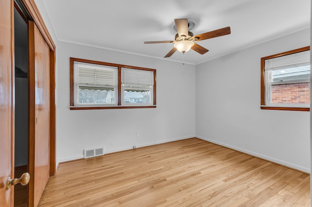 spare room with light wood finished floors, visible vents, and a healthy amount of sunlight