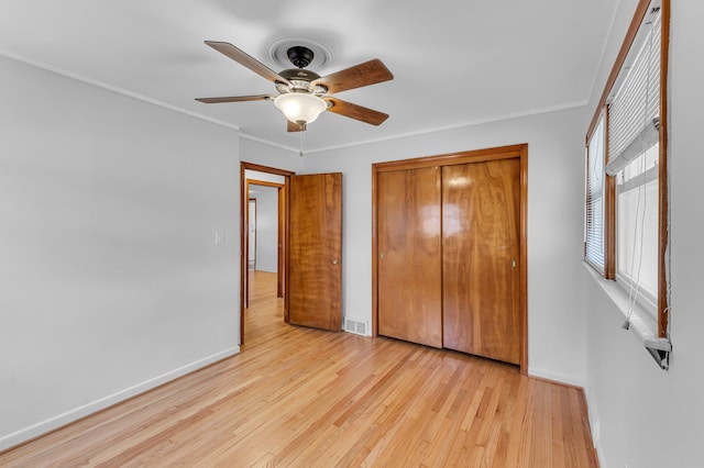 unfurnished bedroom featuring visible vents, crown molding, light wood-style flooring, and baseboards