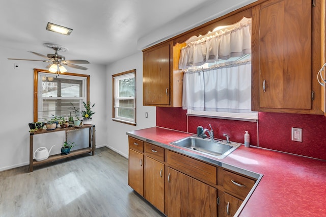 kitchen featuring light wood finished floors, brown cabinets, and a sink