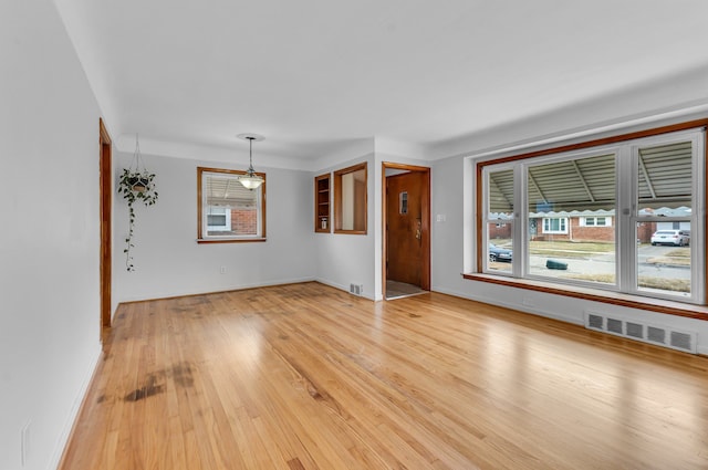 unfurnished living room with light wood-type flooring, visible vents, and baseboards