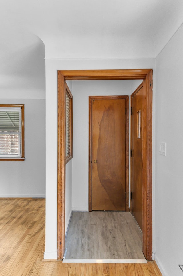 hall with baseboards and wood finished floors