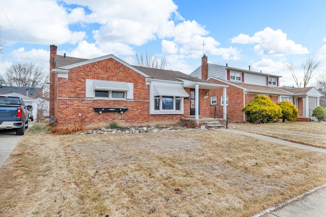 view of front of property with brick siding, concrete driveway, roof with shingles, a chimney, and a front yard