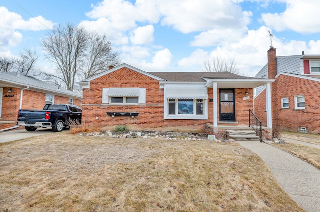 bungalow with a shingled roof, brick siding, and a front lawn