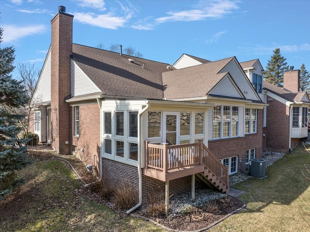 rear view of house with a lawn, central AC, stairway, brick siding, and a chimney