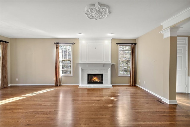 unfurnished living room featuring a wealth of natural light, a brick fireplace, and wood finished floors