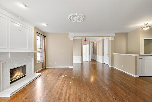 unfurnished living room with baseboards, a brick fireplace, and wood finished floors