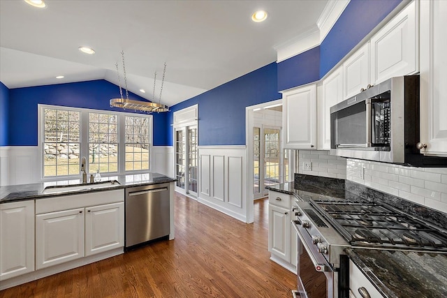 kitchen featuring a sink, a wainscoted wall, appliances with stainless steel finishes, and white cabinetry