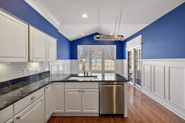 kitchen featuring a sink, a peninsula, white cabinets, dishwasher, and vaulted ceiling