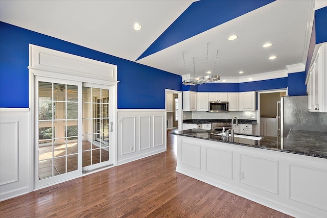 kitchen featuring visible vents, a sink, wainscoting, appliances with stainless steel finishes, and dark wood-style flooring