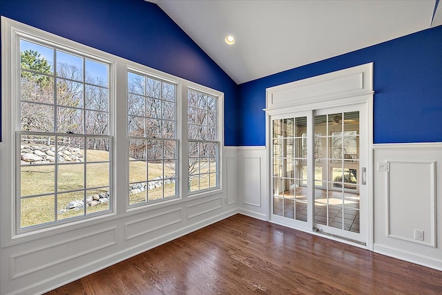 interior space featuring lofted ceiling, a decorative wall, dark wood-type flooring, and wainscoting