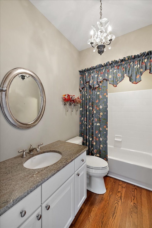 bathroom featuring vanity, wood finished floors, an inviting chandelier, shower / bath combination with curtain, and toilet