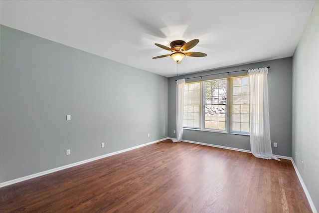 spare room featuring baseboards, dark wood-type flooring, and ceiling fan