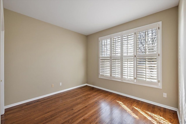 unfurnished room with visible vents, baseboards, and wood finished floors