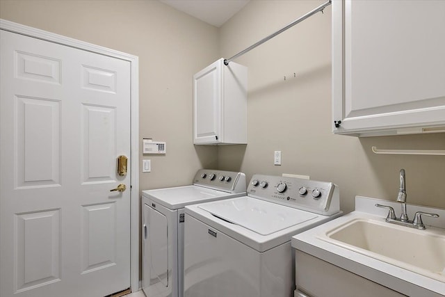 clothes washing area with cabinet space, independent washer and dryer, and a sink