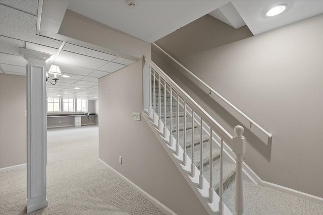 stairs with a drop ceiling, baseboards, and carpet