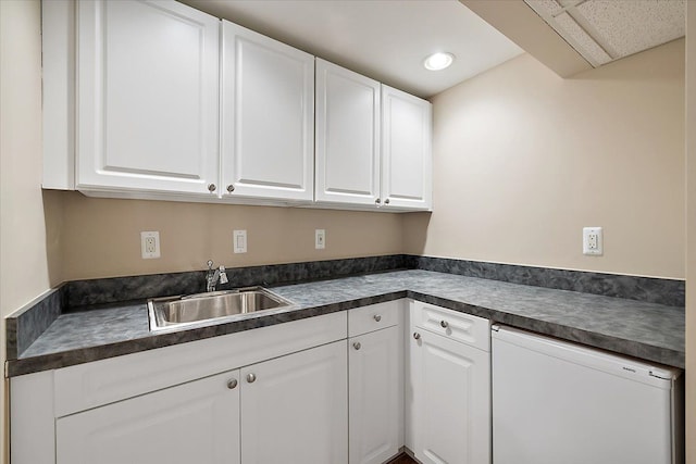 kitchen featuring dark countertops, white cabinets, and a sink