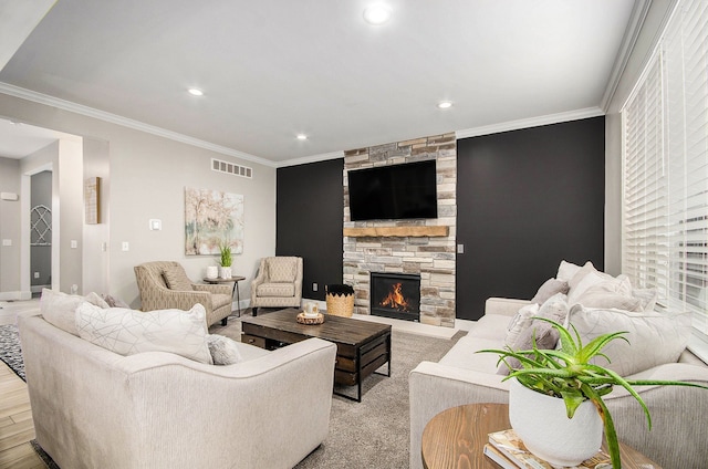 living room featuring ornamental molding, a stone fireplace, visible vents, and recessed lighting