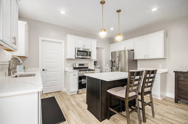 kitchen with stainless steel appliances, a sink, light wood-style flooring, and white cabinetry