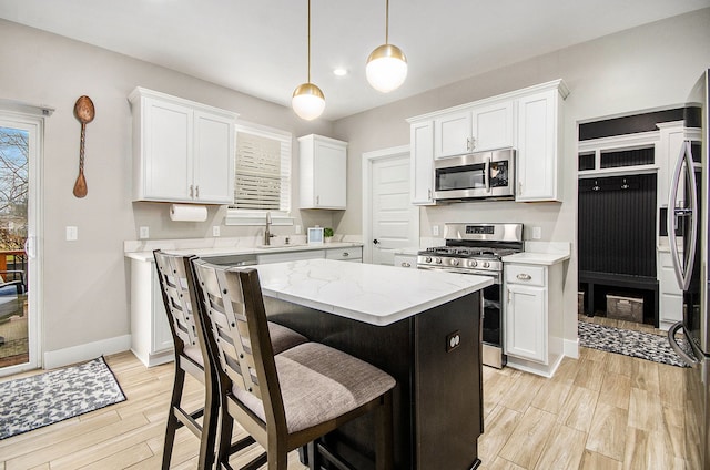 kitchen featuring stainless steel appliances, light wood-type flooring, white cabinets, and a kitchen island