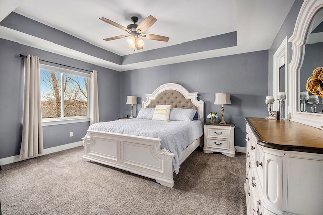 bedroom with dark carpet, ceiling fan, baseboards, and a raised ceiling