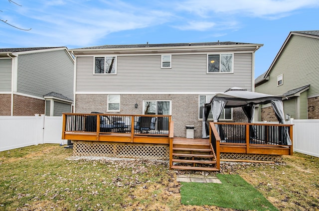 back of house with a fenced backyard, a yard, a wooden deck, and a gazebo