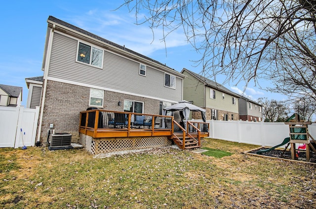 rear view of house featuring central AC unit, a fenced backyard, a yard, a playground, and brick siding