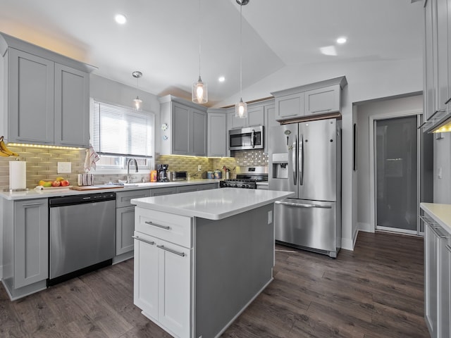 kitchen with dark wood-style floors, pendant lighting, stainless steel appliances, lofted ceiling, and light countertops