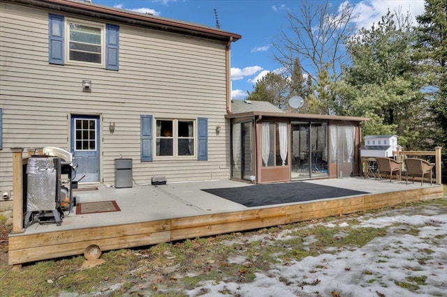 rear view of property featuring a sunroom and a deck