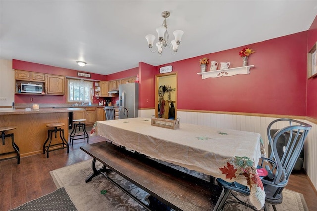 dining room with dark wood-style floors, a chandelier, and a wainscoted wall