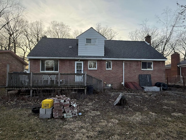 back of house featuring a wooden deck, brick siding, a chimney, and a shingled roof