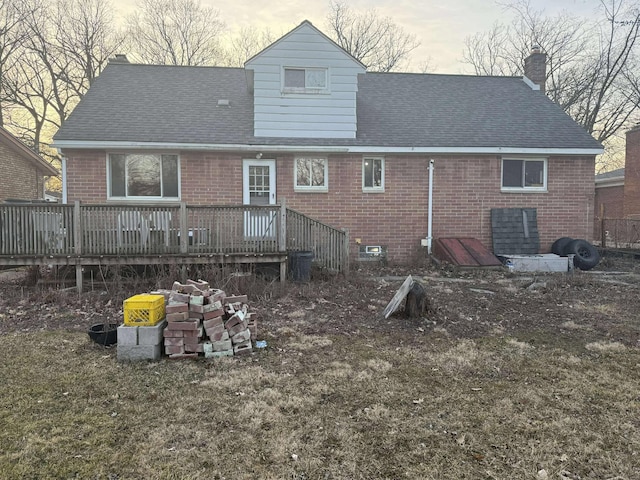 rear view of house with a wooden deck, brick siding, roof with shingles, and a chimney