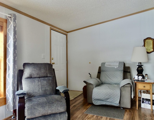 sitting room with ornamental molding, a textured ceiling, and wood finished floors