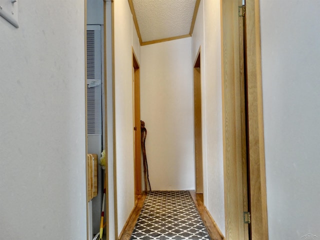 corridor featuring a textured ceiling, ornamental molding, and a heating unit