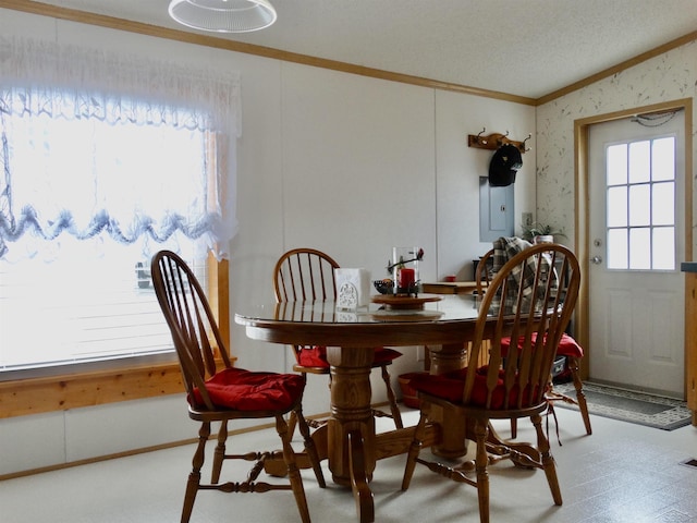 dining space with wallpapered walls, a textured ceiling, ornamental molding, and a wealth of natural light