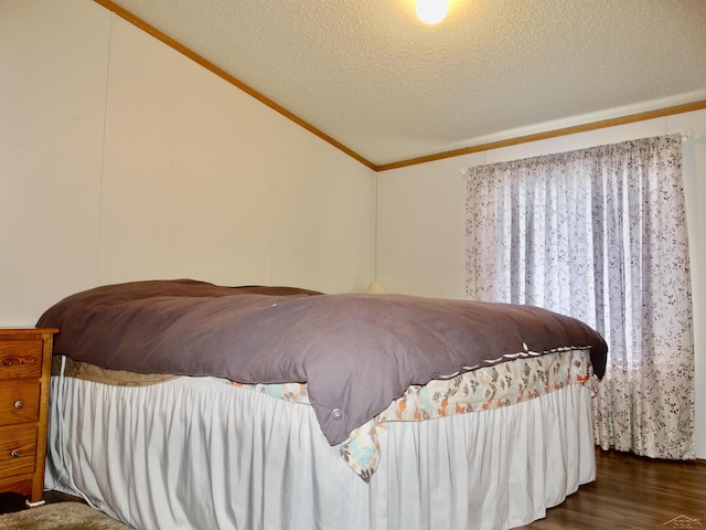 bedroom with ornamental molding, lofted ceiling, a textured ceiling, and wood finished floors