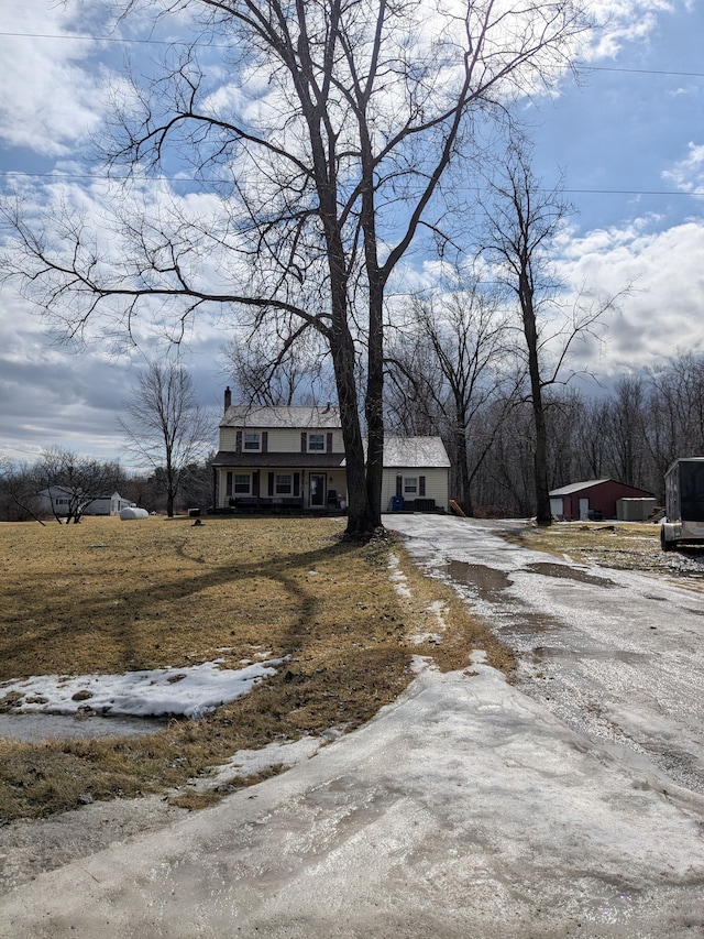 exterior space with a porch, driveway, a chimney, and an outdoor structure