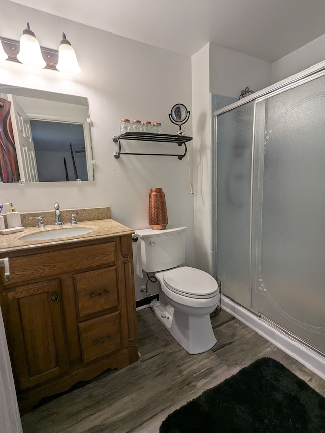 full bath with a stall shower, vanity, toilet, and wood finished floors