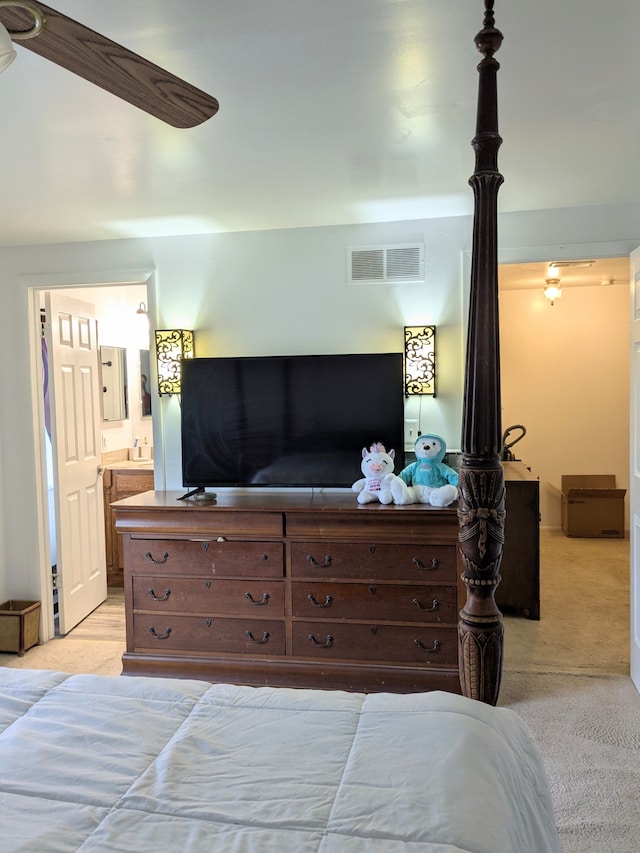 bedroom with light colored carpet, visible vents, and ensuite bathroom